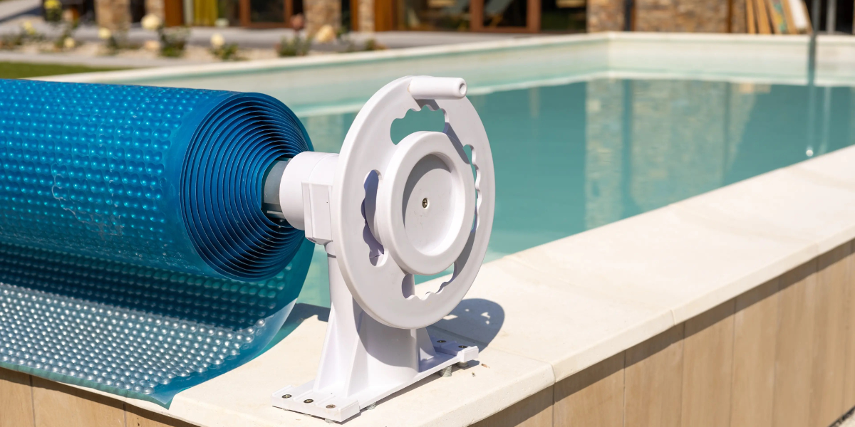 Enrouleur de bâche solaire bleu installé au bord d’une piscine, présenté par Poolplanet pour protéger et chauffer l’eau de la piscine tout en facilitant son entretien.