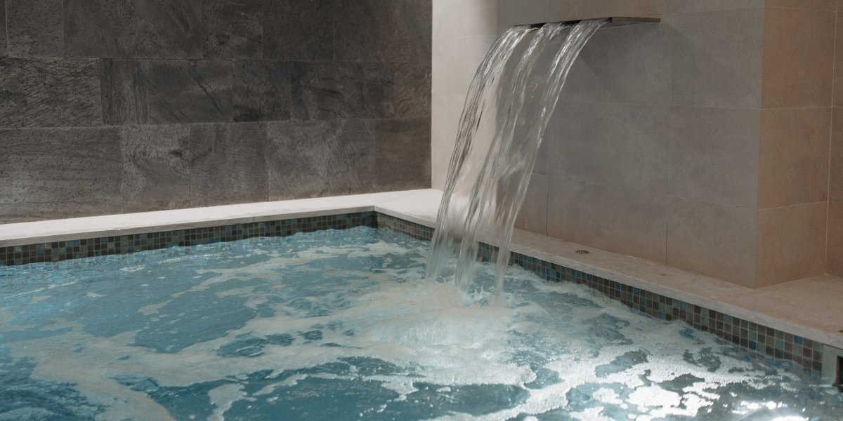 Cascade d’eau dans un bassin intérieur illustrant les déshumidificateurs Poolplanet, conçus pour réguler l’humidité des piscines intérieures, protéger les équipements et garantir un confort optimal.