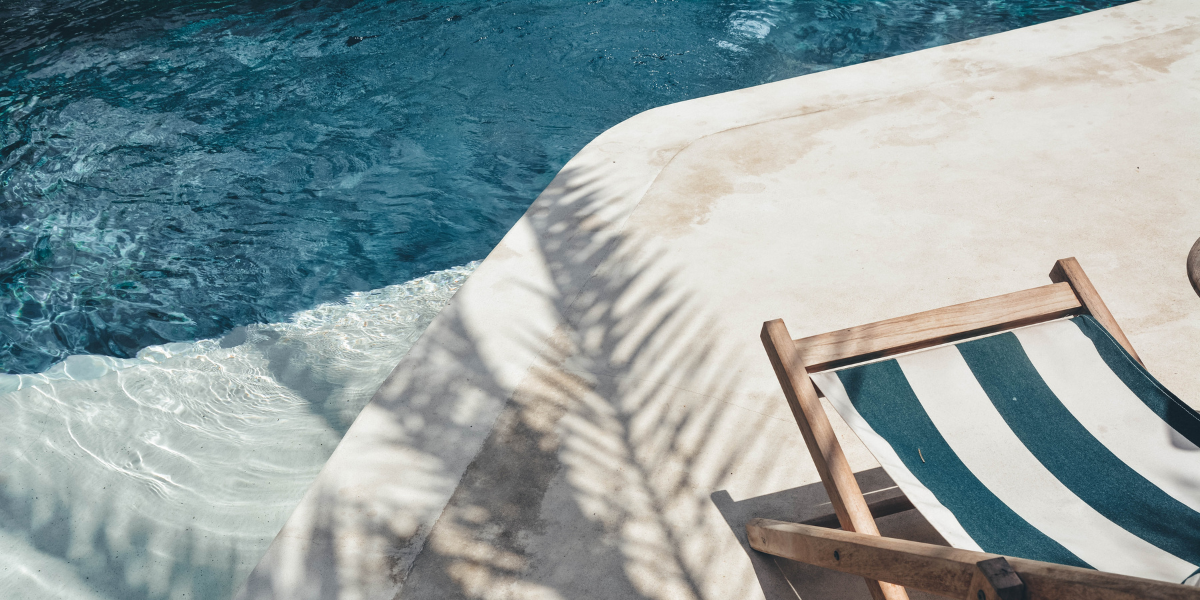 Bord de piscine ensoleillé avec transat, illustrant les pièces détachées Poolplanet pour toutes les catégories : filtration, chauffage, traitement, nettoyage, éclairage et coffrets électriques pour entretenir chaque piscine.