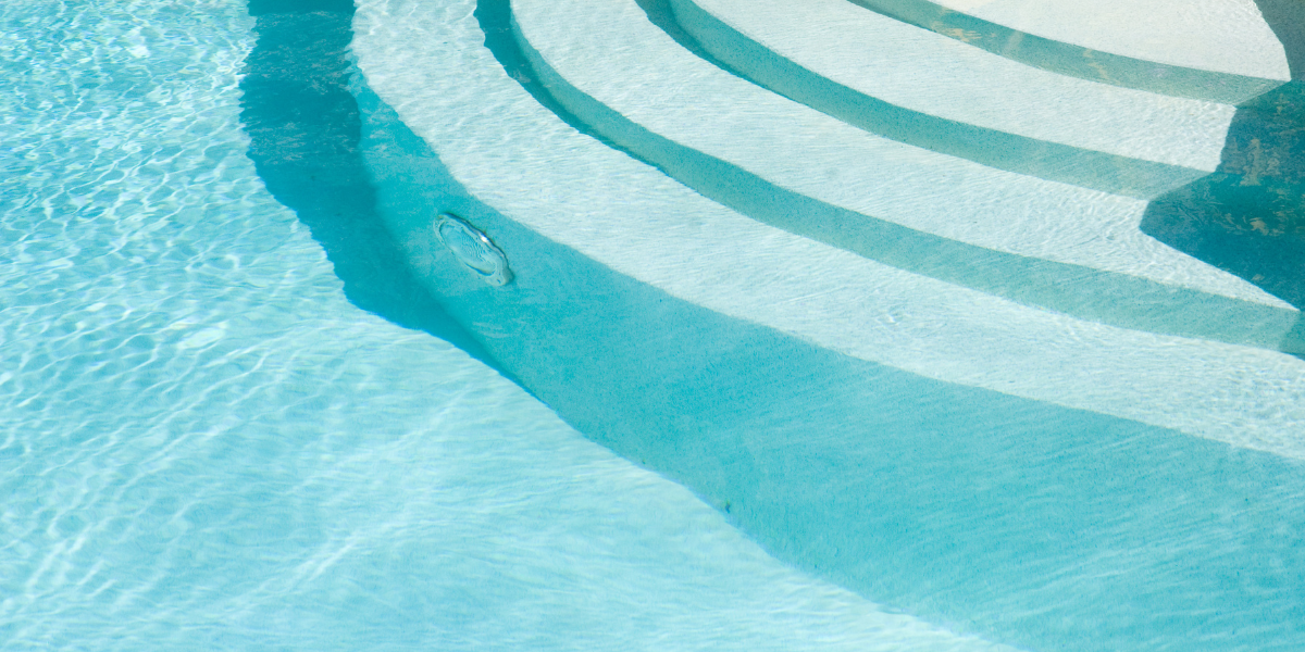 Marches immergées éclairées illustrant les projecteurs et ampoules PAR56 Poolplanet, idéals pour remplacer ou moderniser l’éclairage sous-marin des piscines avec une lumière puissante et durable.