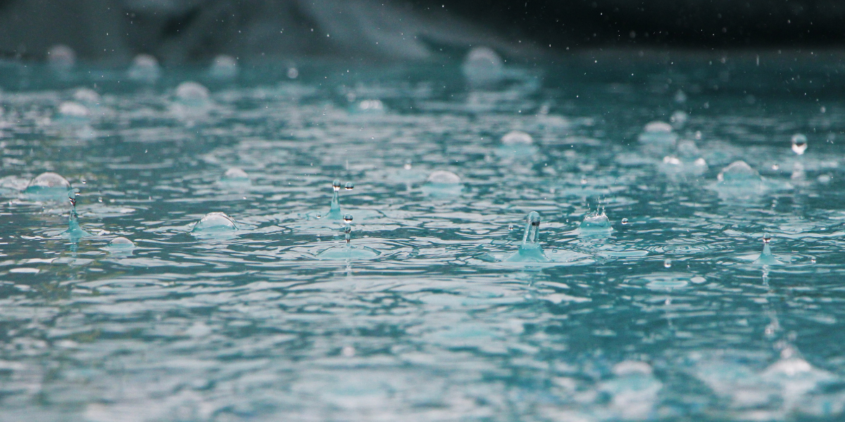 Gouttes de pluie à la surface d’une piscine illustrant les coffrets de régulation de niveau Poolplanet, systèmes automatiques conçus pour maintenir un niveau d’eau constant et éviter tout débordement ou manque d’eau.