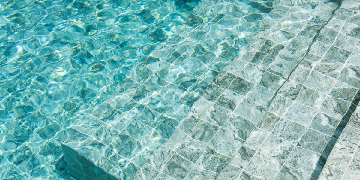 Vue claire d’une piscine ensoleillée symbolisant les coffrets répartiteurs Poolplanet, essentiels pour distribuer efficacement l’alimentation électrique entre les différents équipements de la piscine.